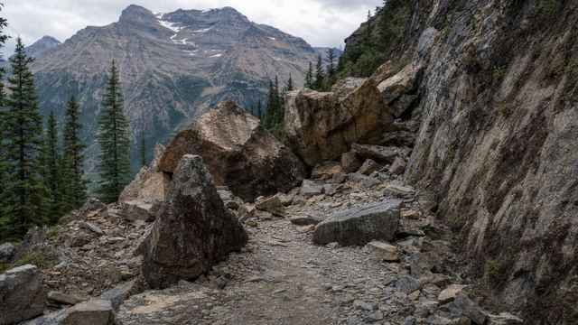 Barrière et panneau d’avertissement en travers d’un sentier de montagne fermé après un éboulement