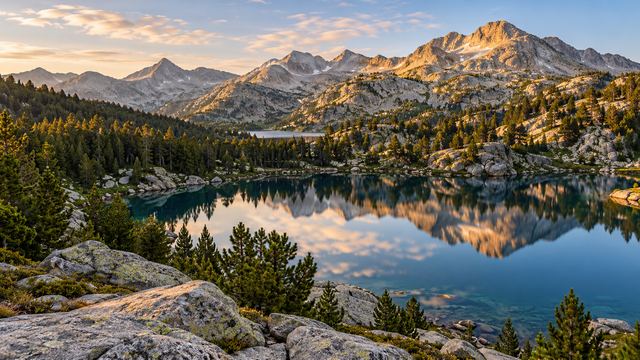 Un lac de montagne bordé de pins à crochets au pied du massif granitique du Néouvielle, par temps clair